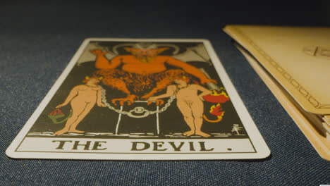 Close-Up-Shot-Of-Person-Giving-Tarot-Card-Reading-Laying-Down-The-Devil-Card-On-Table